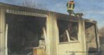 Ein Teil der völlig ausgebrannten Obdachlosenunterkunft. Feuerwehrleute entfernen Teile der Dachkonstruktion.brFoto: Volksstimme